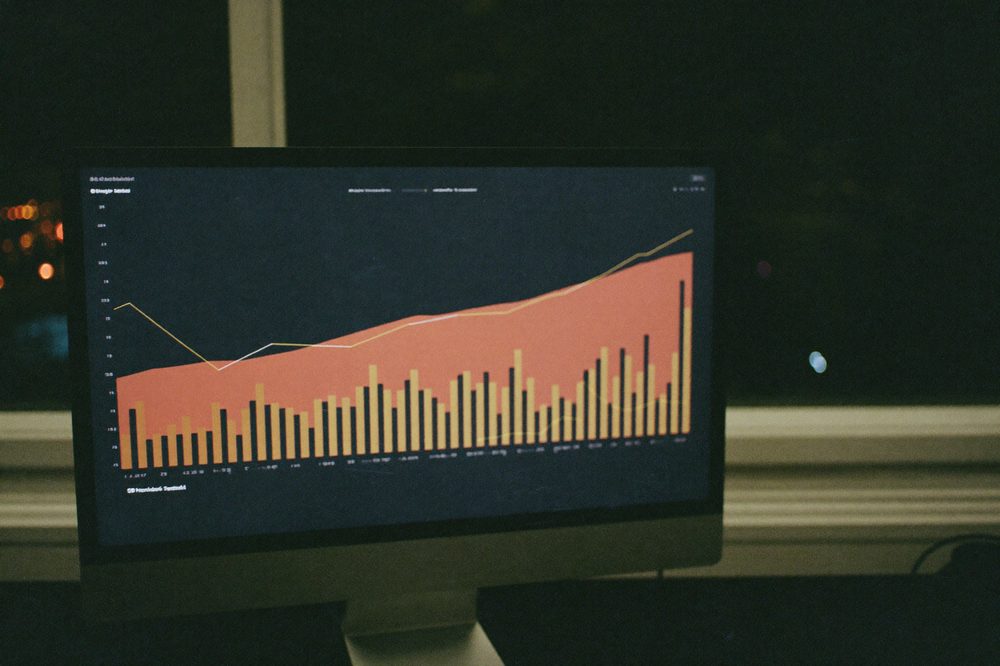 An analytics dashboard glows on a monitor at night with upward-trending charts